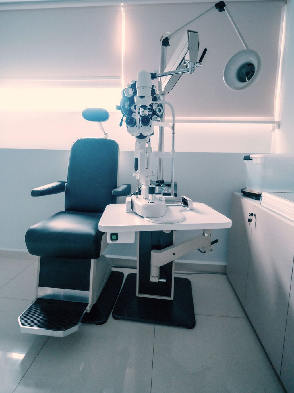 An ophthalmology exam room with an exam chair and refraction equipment.