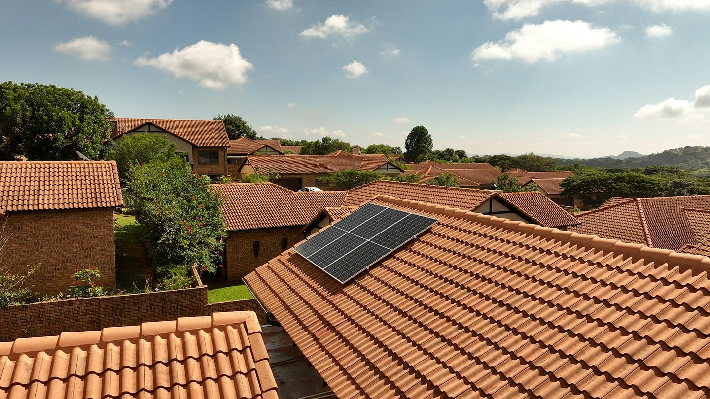View from above of a neighborhood of tile-roofed houses; on one of them, a six-panel solar array sits on the upper part of the front-facing plane.