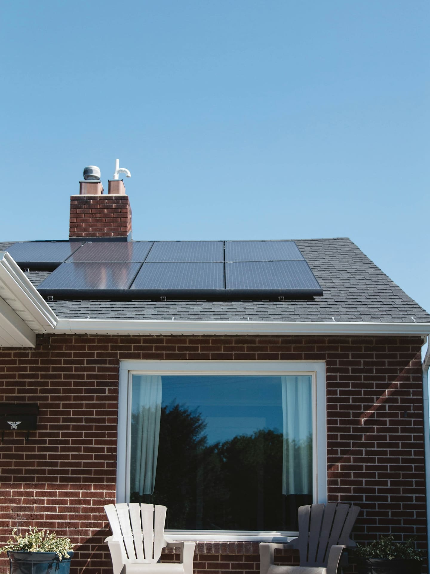 Brick house with solar panels covering the upper half of the roof plane, seen from the street.